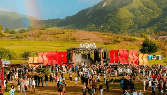 Shabang festival main stage beneath green hills with a rainbow overhead